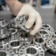 A worker inspects and sorts round parts with holes